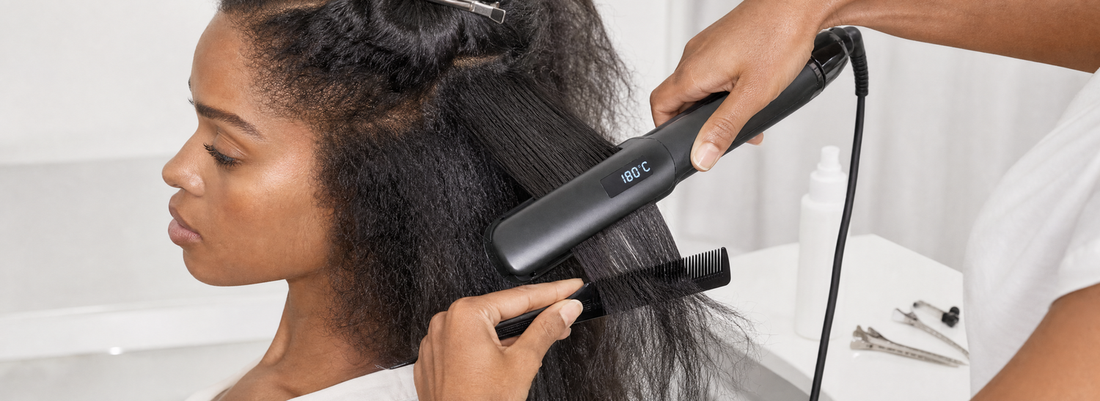 Digital flat iron beside sectioned, smooth hair, a heat-protectant bottle, comb, and temperature guide on a professional salon workstation